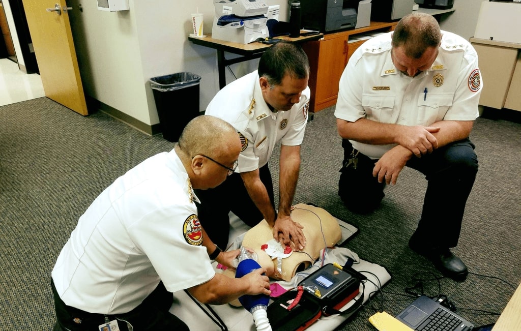 Three men doing CPR on a training dummy
