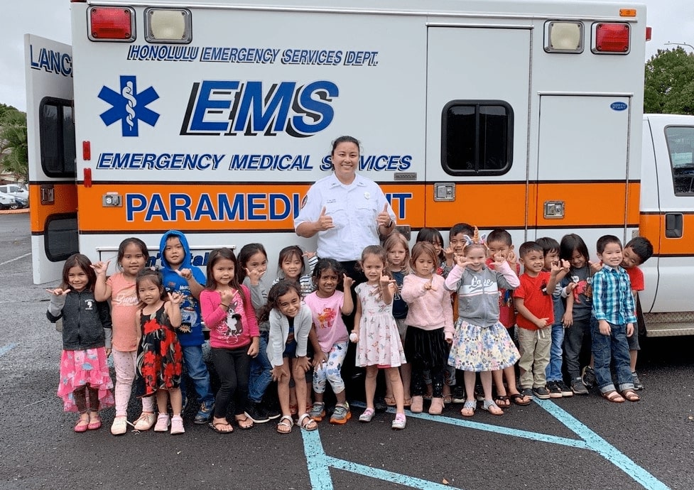 Group of kids posing in front of an ambulance